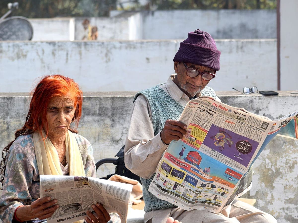 Elderly couple reading newspapers together on a terrace